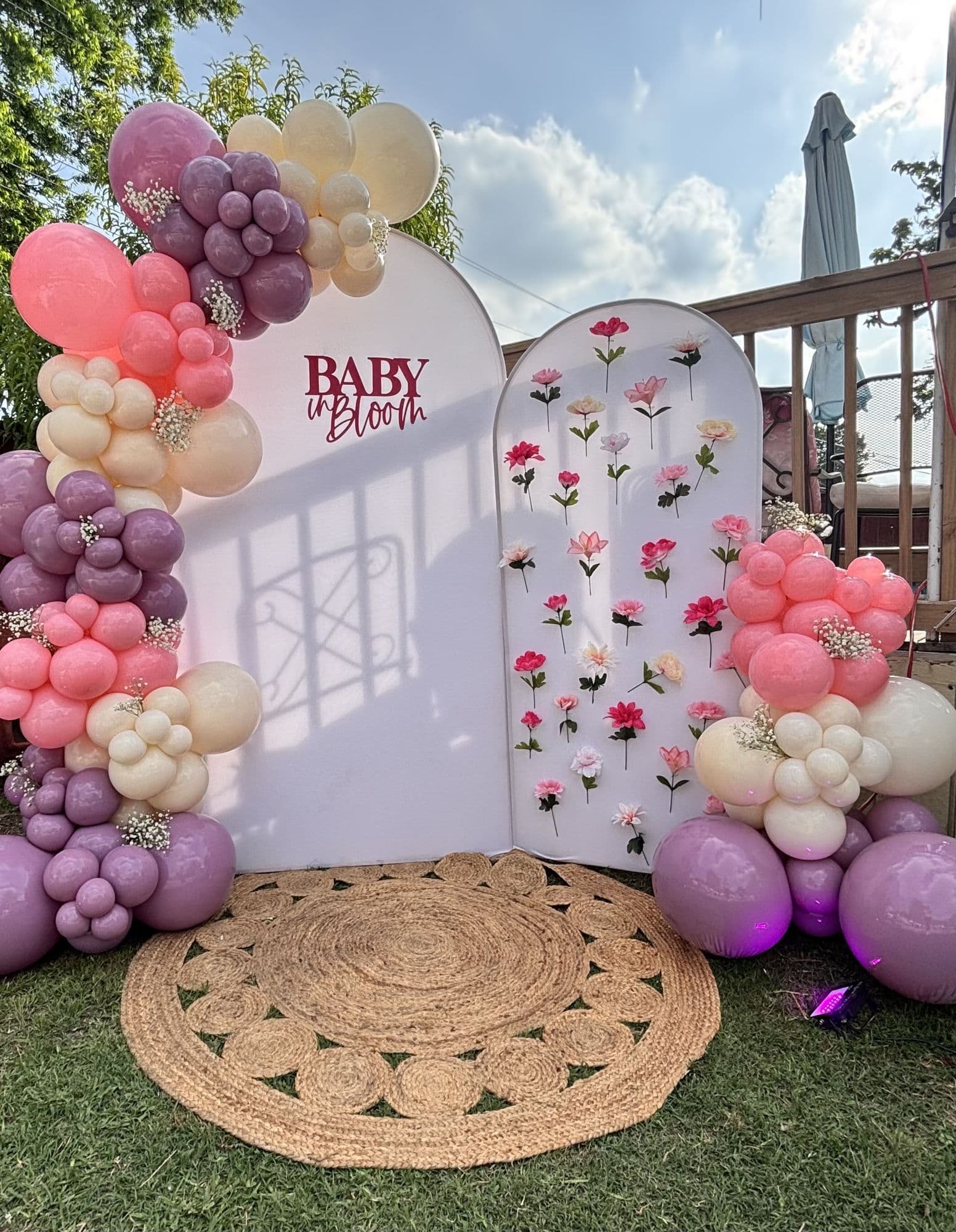 Pink, lavender and purple balloon garland on a Baby in Bloom arch backdrop with a floral panel