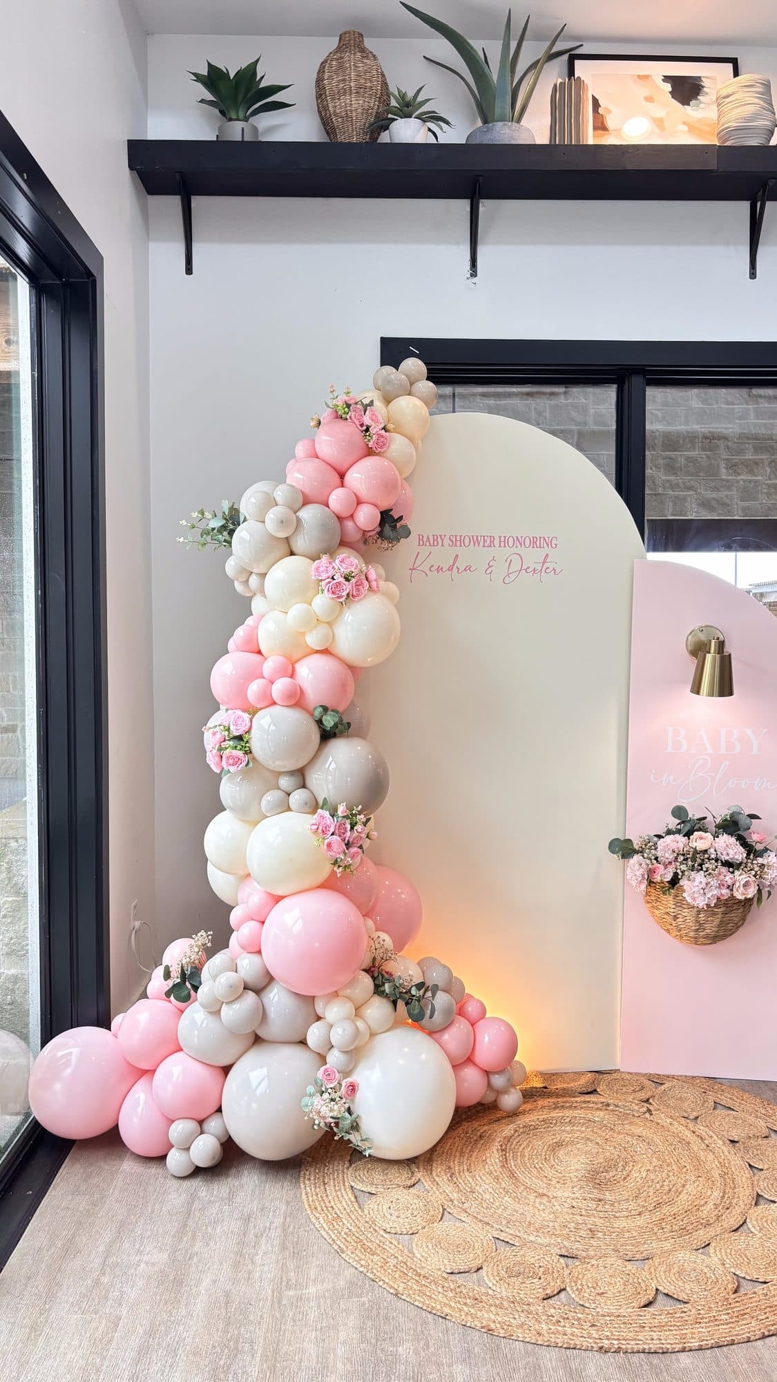Blush pink and cream organic balloon garland on a two-tone arch wall with floral wall sconces for a baby shower