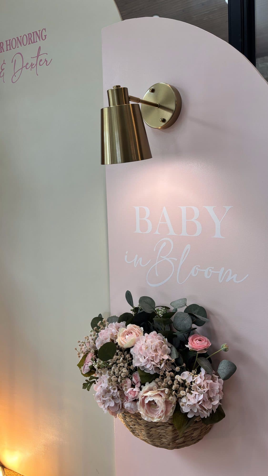 Detail of a floral wall sconce and a Baby in Bloom sign beside the blush and cream balloon garland