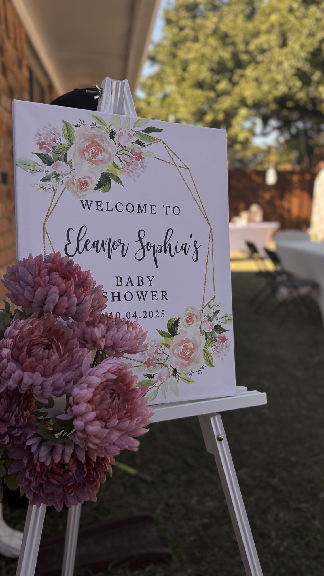 Floral welcome sign on an easel with fresh flowers at an outdoor baby shower