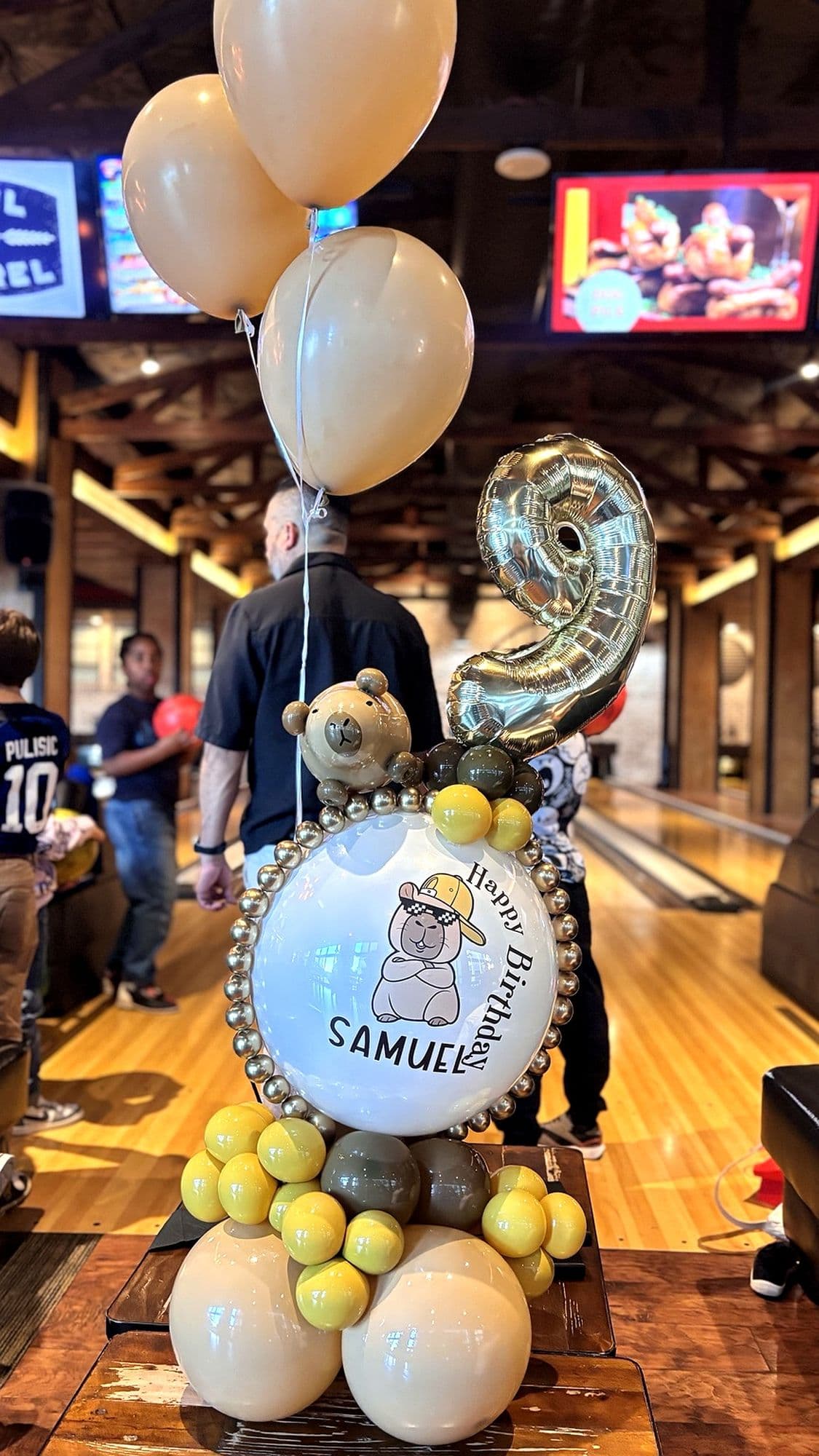 Birthday balloon bouquet with a number 9 balloon, a bear-themed bubble balloon and yellow and cream balloons