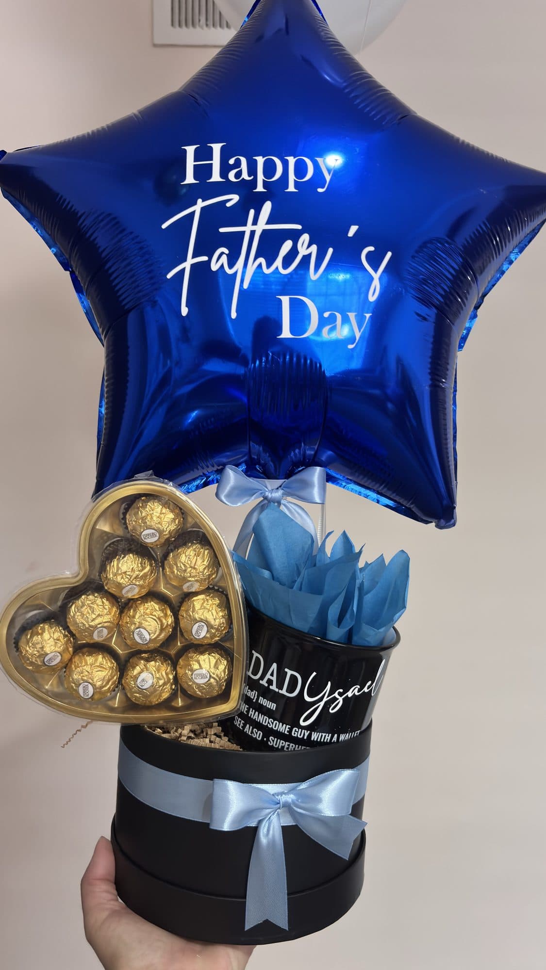 Happy Father's Day star balloon bouquet with a chocolate heart gift box, held in hand