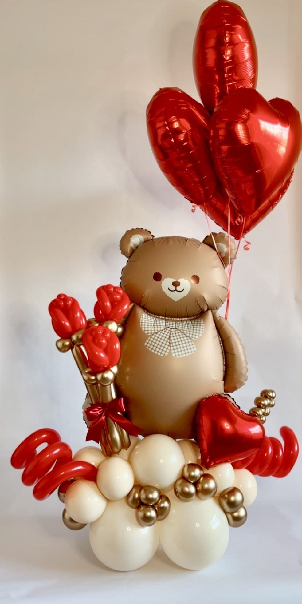 Valentine balloon bouquet with a teddy bear foil balloon, red heart balloons and gold accents