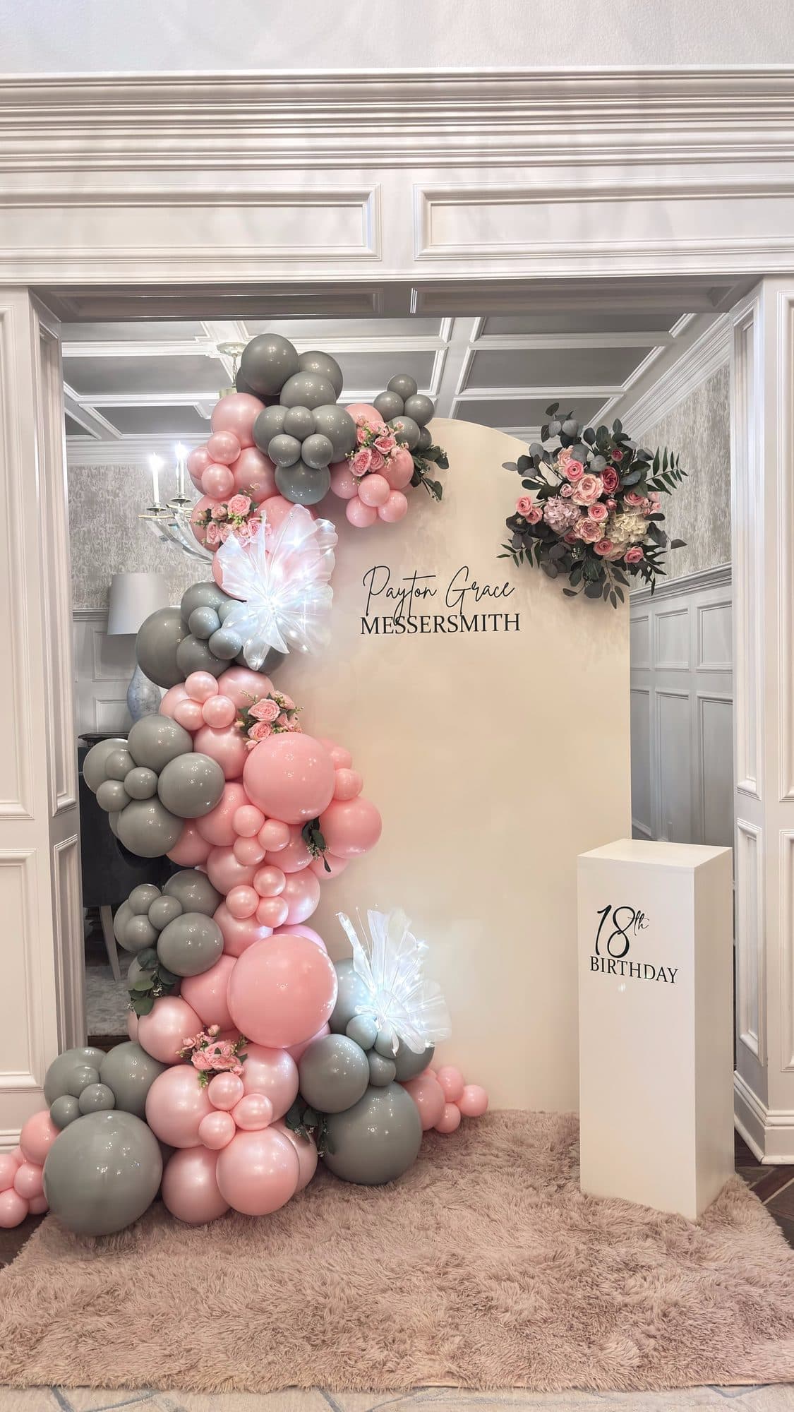 Sage and blush balloon garland with white feather and floral accents on an arched alcove backdrop for an 18th birthday