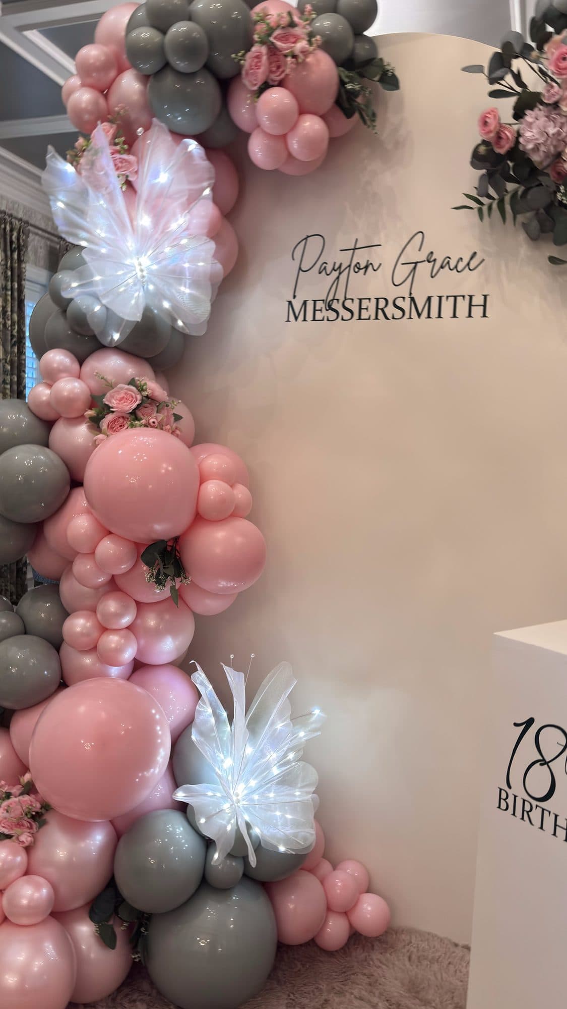 Close-up of the sage and blush balloon garland with feather and floral accents on the 18th birthday backdrop