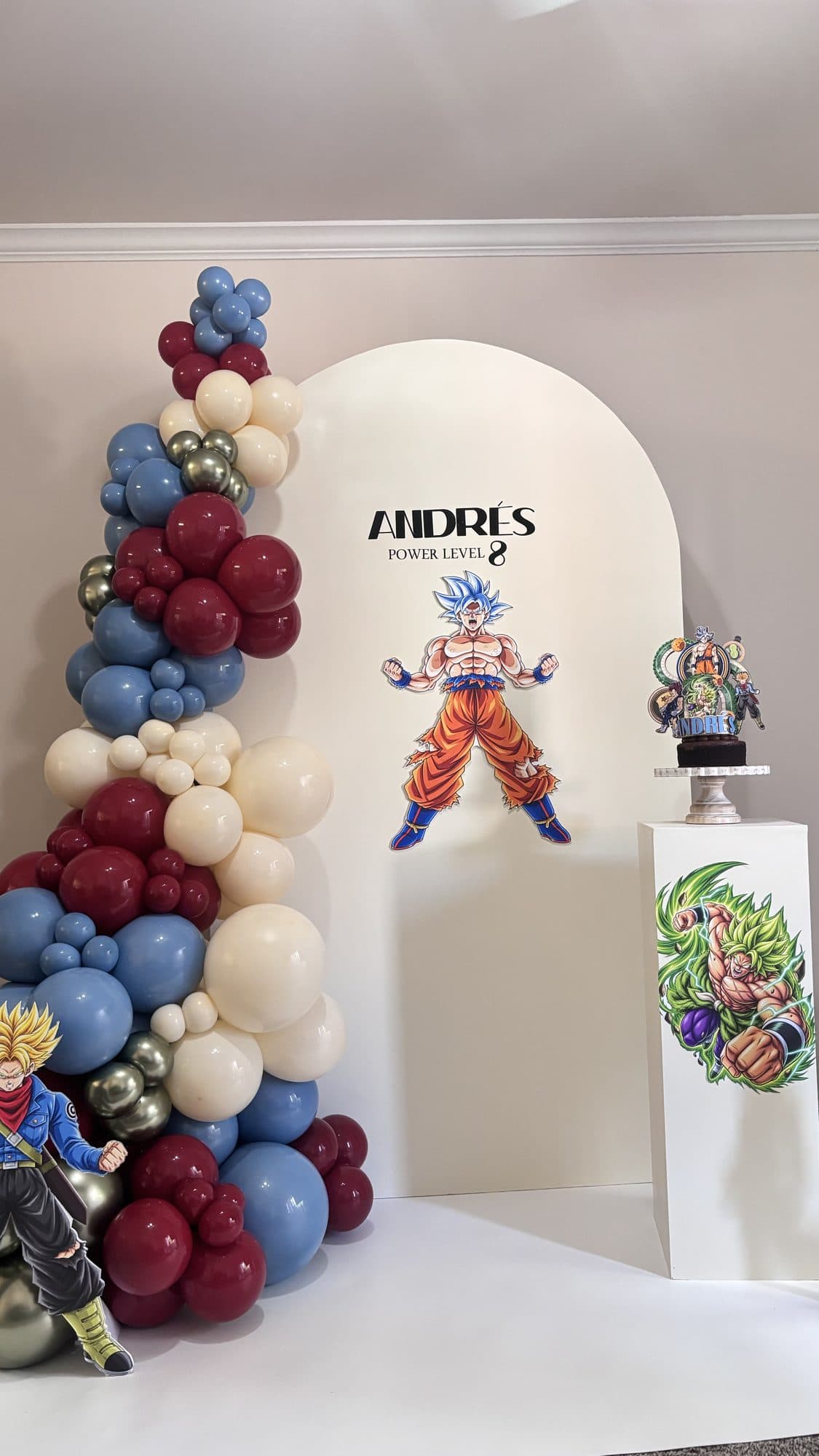 Dragon Ball Z themed balloon backdrop in red, blue and cream with character cutouts and a power level sign