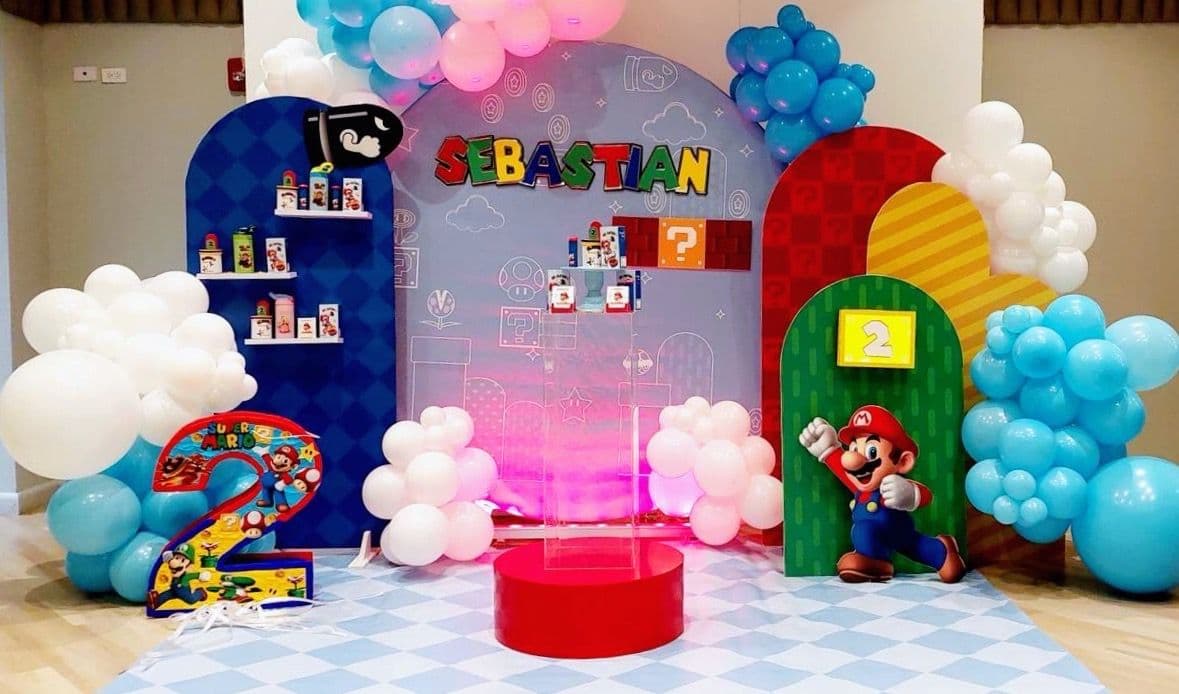 Video game themed birthday backdrop with colorful balloon garlands and a red centerpiece