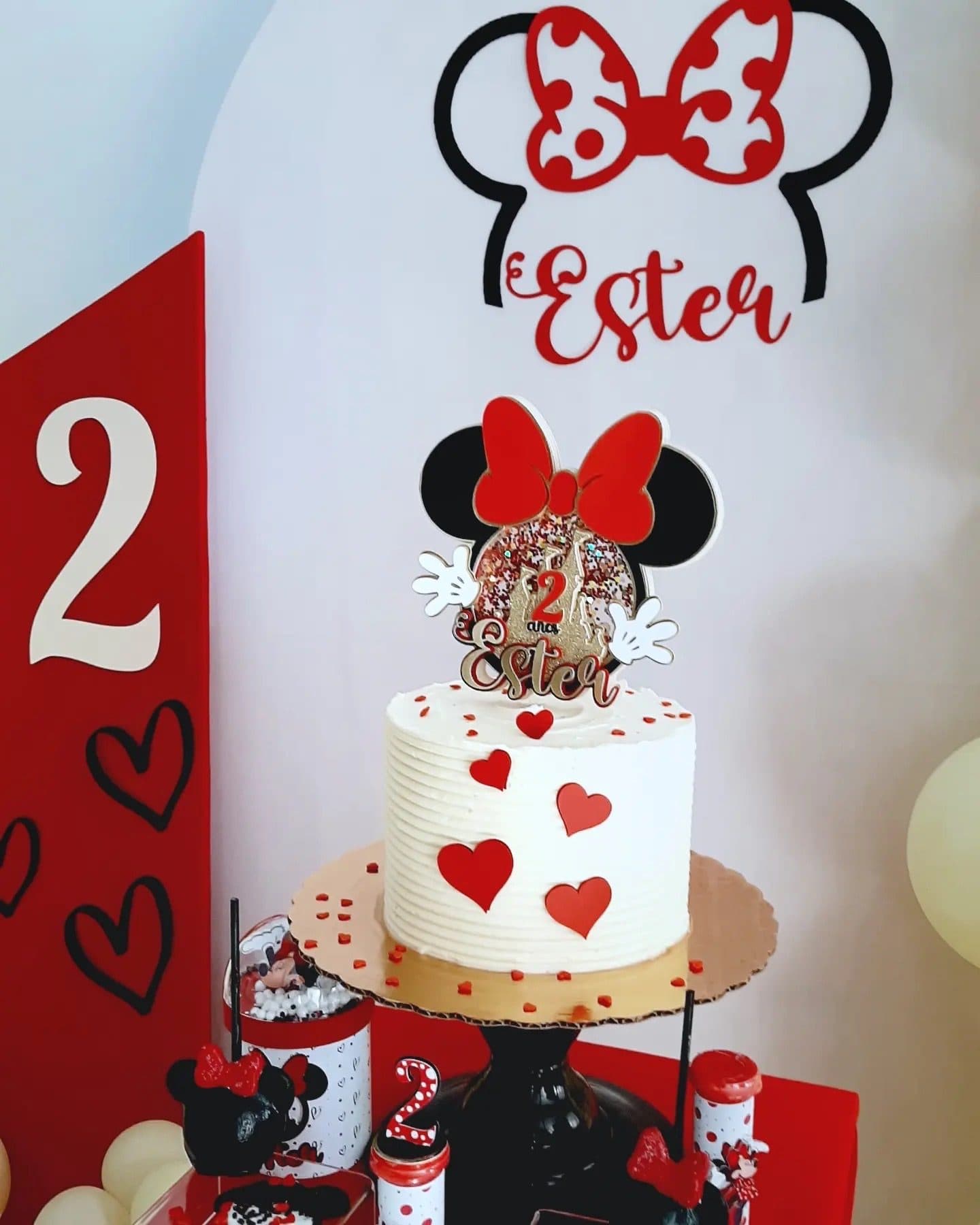 Red, white and black Minnie Mouse themed dessert table with a number 2 and heart-covered cake