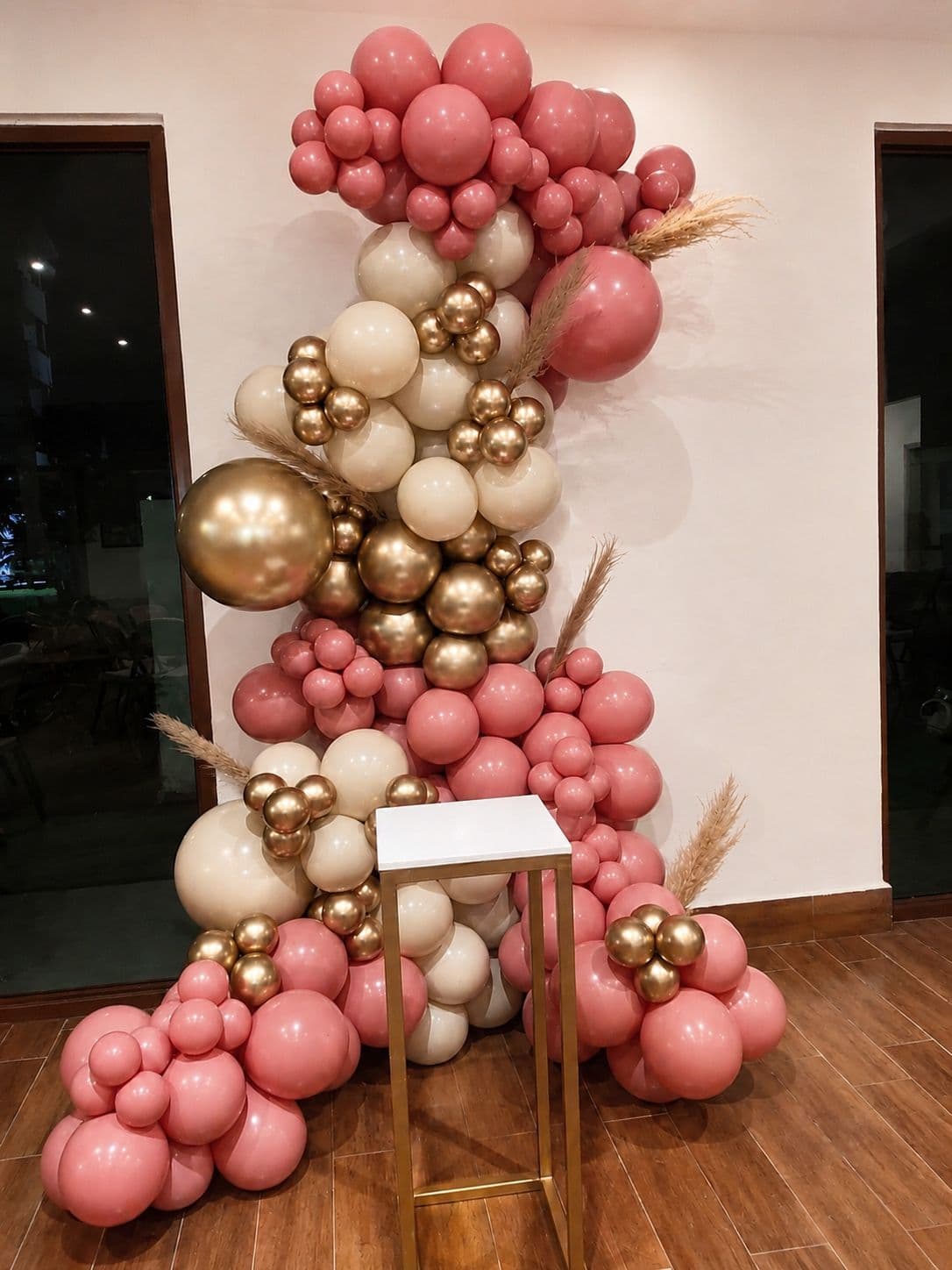 Pink, cream and chrome gold balloon garland with pampas grass and a gold stand for a birthday