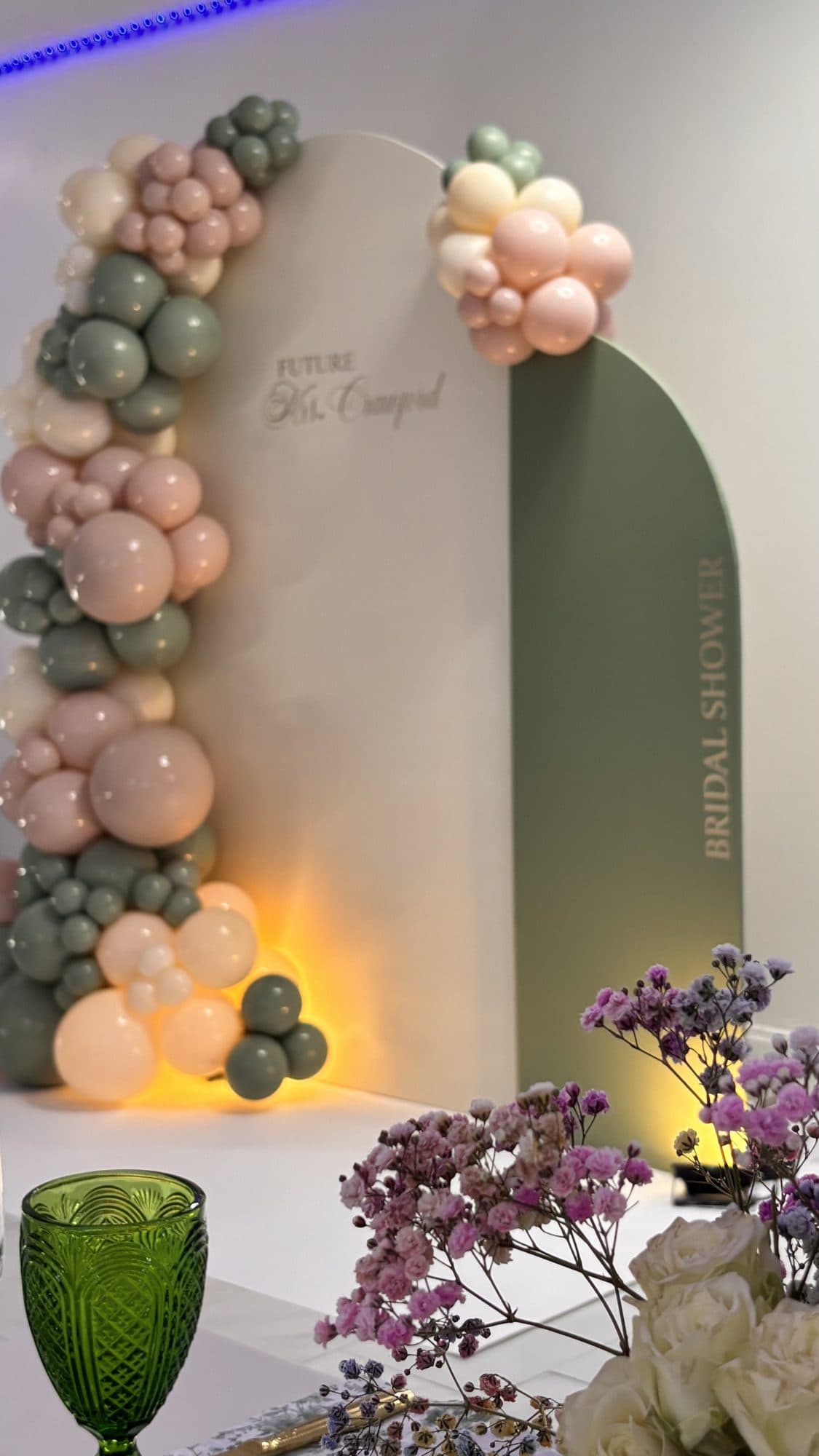 Detail of a sage green, blush and cream organic balloon arch with fresh flowers