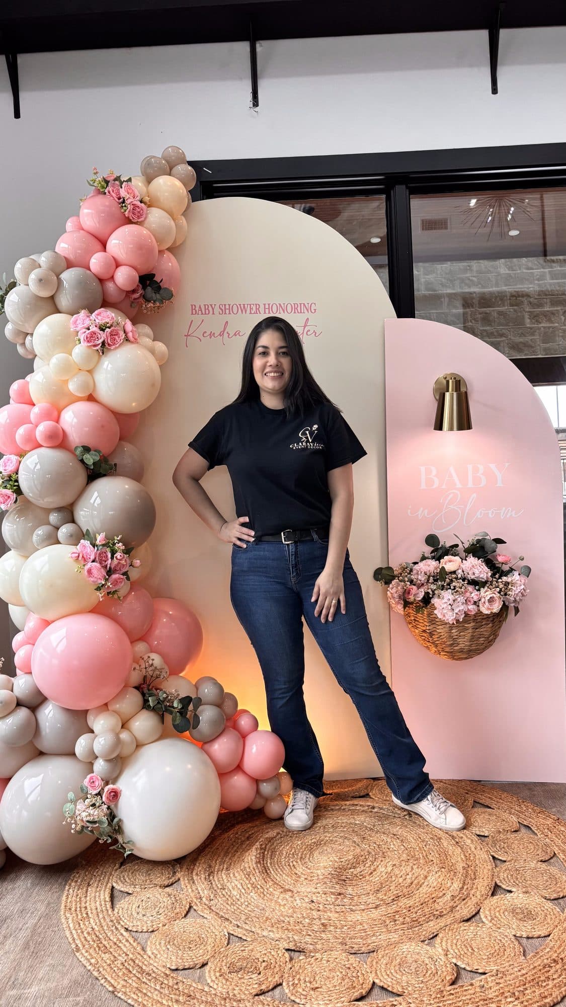 Clara Vento standing in front of the blush pink and cream baby shower balloon arch
