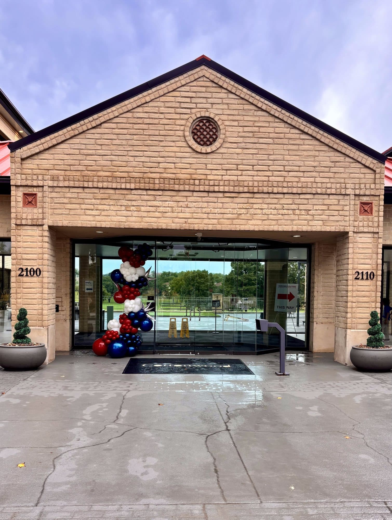 Navy, red and white balloon garland framing the brick entrance of an office building