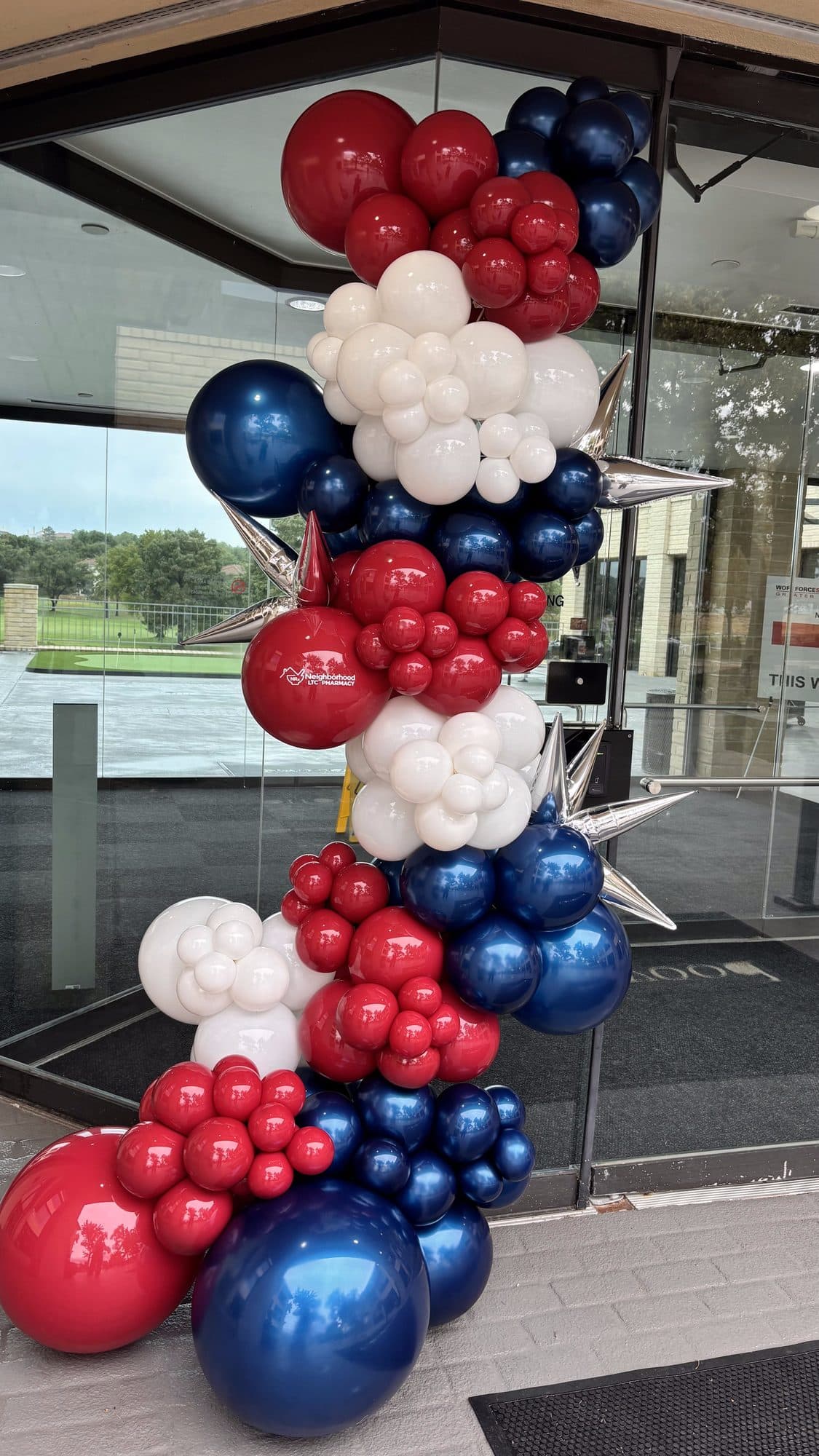 Detail of a navy, red and white balloon garland cascading along a glass office doorway