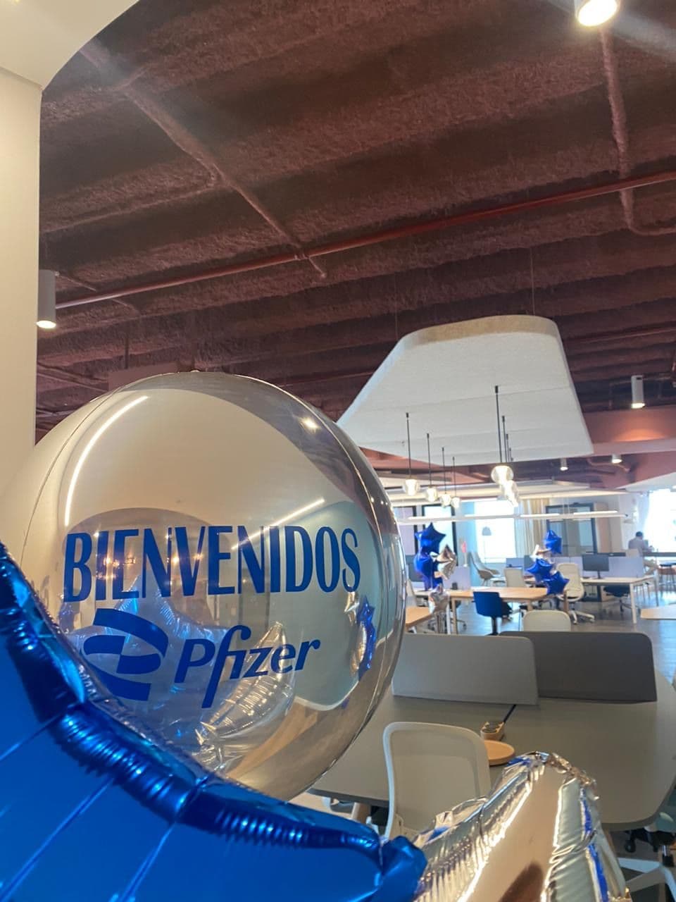 Clear bubble balloon with a Bienvenidos welcome message and blue foil balloons at a corporate office