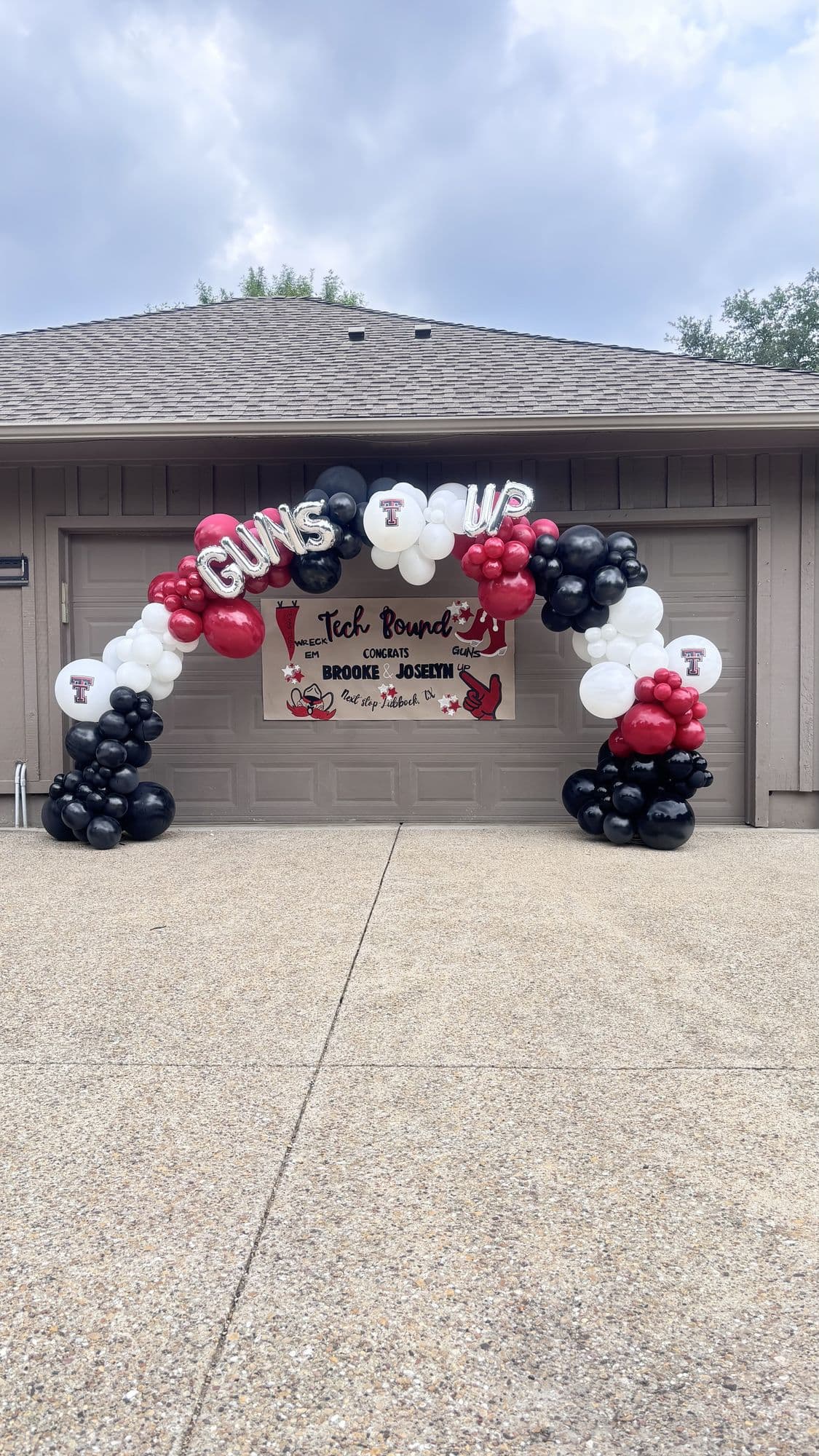 Red, black and white balloon arch over a garage door for a college-bound graduation party