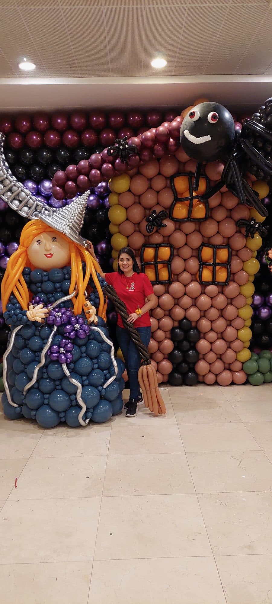 Balloon sculpture of two witches beside a haunted gingerbread-style house for a Halloween display