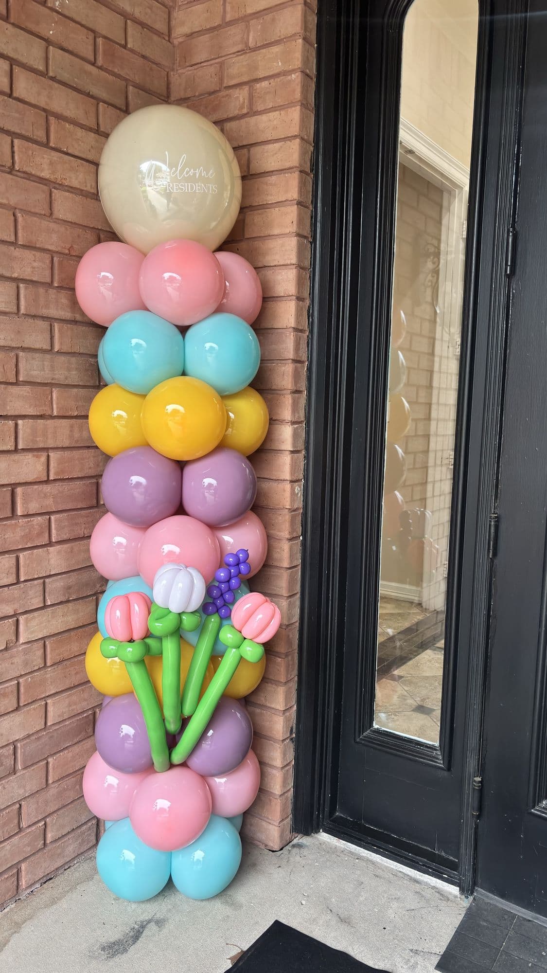 Pastel balloon column with tulip balloons framing a front door for a spring celebration